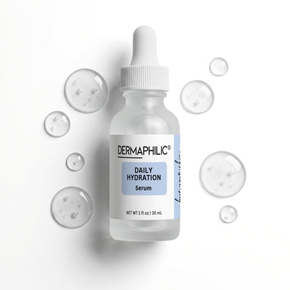 Frosted glass bottle with dropper labeled 'Dermaphilic Daily Hydration Serum'  and drops of serum beside bottle on a white background 